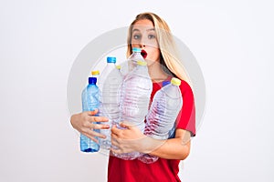 Young beautiful woman recycling plastic bottles standing over isolated white background scared in shock with a surprise face,