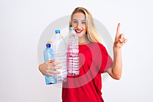 Young beautiful woman recycling plastic bottles standing over isolated white background surprised with an idea or question