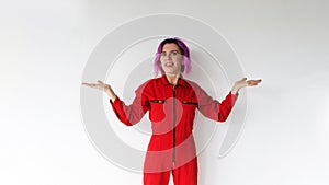 A young beautiful woman in a red jumpsuit looks forward with a smile, arms outstretched on a white background. A place