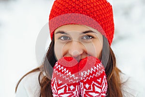 Young beautiful woman in red knitted hat and mittens in winter forest. Snowy day autdoors