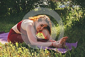 Young beautiful woman in red leggings and a top practicing yoga in a city park