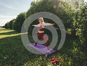 Young beautiful woman in red leggings and a top practicing yoga in a city park