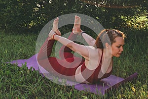 Young beautiful woman in red leggings and a top practicing yoga in a city park