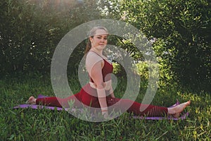 Young beautiful woman in red leggings and a top practicing yoga in a city park