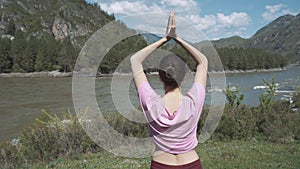 Young beautiful woman in red tank top practicing outdoors, doing Bending Tree posture, variation of Vrksasana, in park