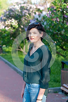 Young beautiful woman relaxes among the flowering bushes of lilac