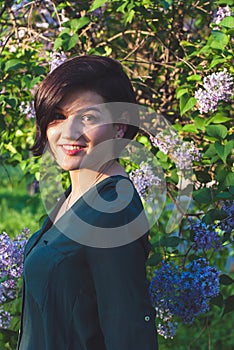 Young beautiful woman relaxes among the flowering bushes of lilac