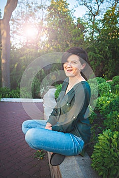 Young beautiful woman relaxes among the flowering bushes of lilac