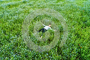 Young beautiful woman relaxing in the field with flowers. Overhead view.