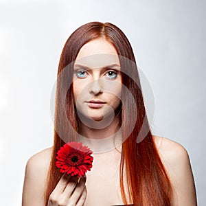 Young beautiful woman relaxing with gerbera flower at spa isolated