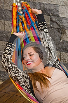 Young beautiful woman relaxing in a hammock in garden, in blurred background