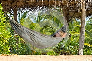 Young beautiful woman relaxing in hammock in a tropical resort.