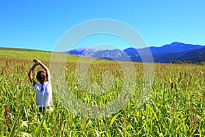 Young beautiful woman relaxing in the middle of a green cereals field during the last days of summer in the Pyrenees mountains