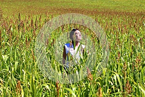 Young beautiful woman relaxing in the middle of a green cereals field during the last days of summer in the Pyrenees mountains