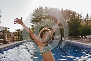young beautiful woman relaxing at the swimming pool at sunset. Vacation lifestyle outdoors