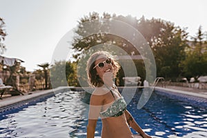 young beautiful woman relaxing at the swimming pool at sunset. Vacation lifestyle outdoors