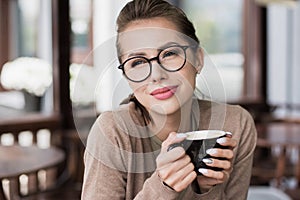 Young beautiful woman resting at cafe. Pretty student girl drinking coffee outdoors.