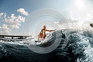 young beautiful woman rides down the wave on a wakeboard