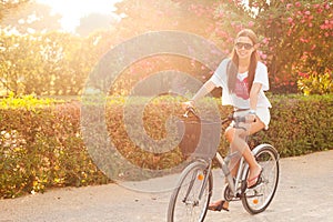 Young beautiful woman riding bicicle on summer photo