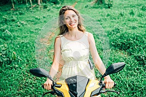 Young beautiful woman riding scooter. Tropical travel concept