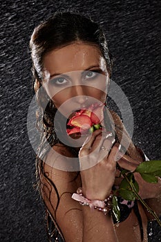 Young woman with rose under rain.