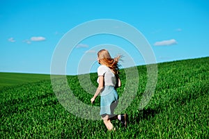 Young beautiful woman running on a green field