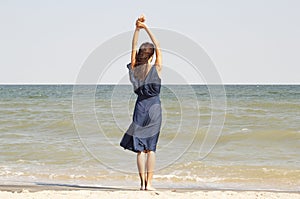 Young beautiful woman at seaside in blue dress