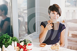 Young beautiful woman with short hair drinking steaming coffee