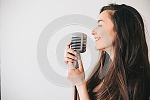Young beautiful woman sing in vintage microphone.