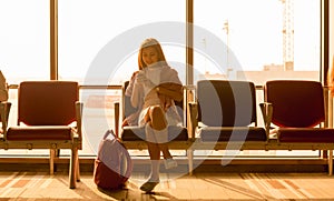 Young beautiful woman sit in airport with travel bag use smartphone with ear phone at airport wait for flight, world exploration