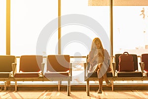 Young beautiful woman sit in airport with travel bag use smartphone with ear phone at airport wait for flight, world exploration