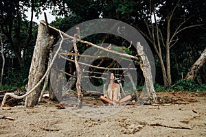 Young beautiful woman sits in lotus position on on background tropical forest