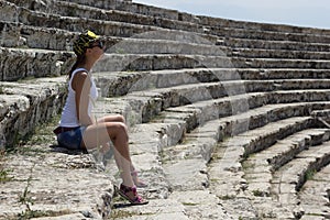 Young beautiful woman sitting in the amphitheater