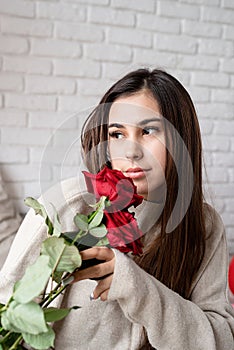 Young beautiful woman sitting in the bed celebrating valentine day holding red roses