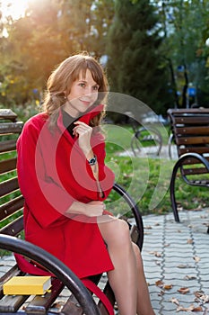 Young beautiful woman sitting on a bench in autumn Park