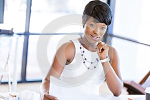 Young woman sitting at a desk in an office and working on blueprint