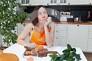 Young beautiful woman sitting at kitchen background while cooking