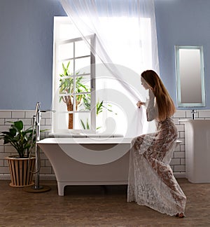 Young beautiful woman sitting near bathtub ready for taking bath near