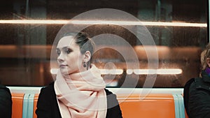 Young beautiful woman sitting in subway. Attractive thoughtful girl goes to work by public transport.