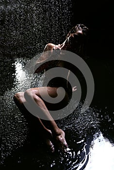 Young beautiful woman sitting under the rain water drops water s