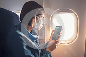 Young beautiful woman sitting at window of plane during the flight