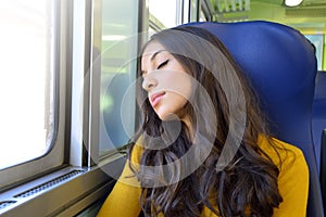 Young beautiful woman sleeping sitting in the train. Train passenger traveling sitting in a seat and sleeping