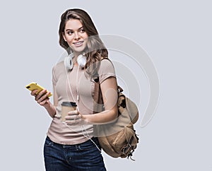 Young beautiful woman with smart phone. Smiling student girl going on a travel. Isolated on gray background