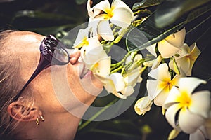 Young beautiful woman smelling tropical flowers during her travel vacation