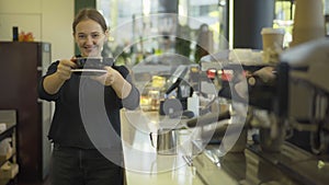 Young beautiful woman smiling at camera and stretching cup with delicious fresh coffee. Portrait of professional