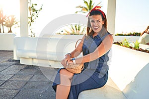 Young beautiful woman smiling happy sitting on a bench of Puerto de la Cruz, Tenerife on a sunny day of summer