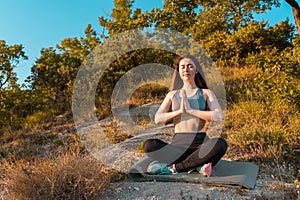 Young beautiful woman smiling and meditating in the Park. Sunset. The concept of yoga, sports and meditation