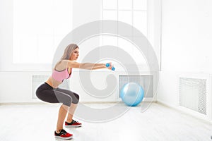 Young beautiful woman in sportswear doing squat