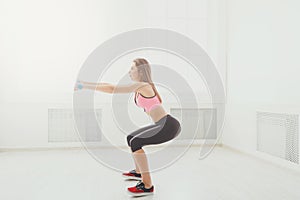 Young beautiful woman in sportswear doing squat