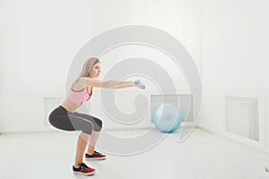 Young beautiful woman in sportswear doing squat